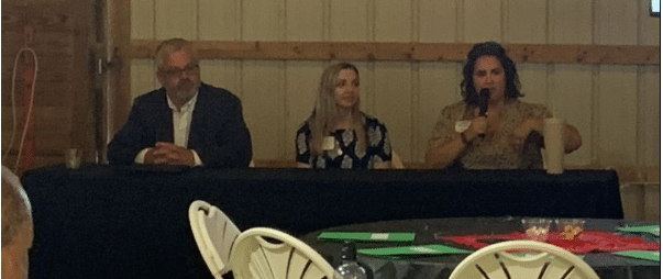 Three individuals sit at a table discussing farming.