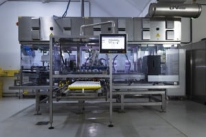 HatchTech Group’s stainless steel Circuit machine in a room with a tray of eggs near its bottom and a arm with a computer screen reaching out from the top of the machine above the eggs