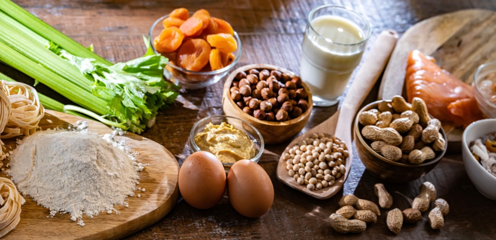 Some of the top food allergens including eggs, wheat, nuts, dairy, fish, and soybeans are displayed on a cutting board.