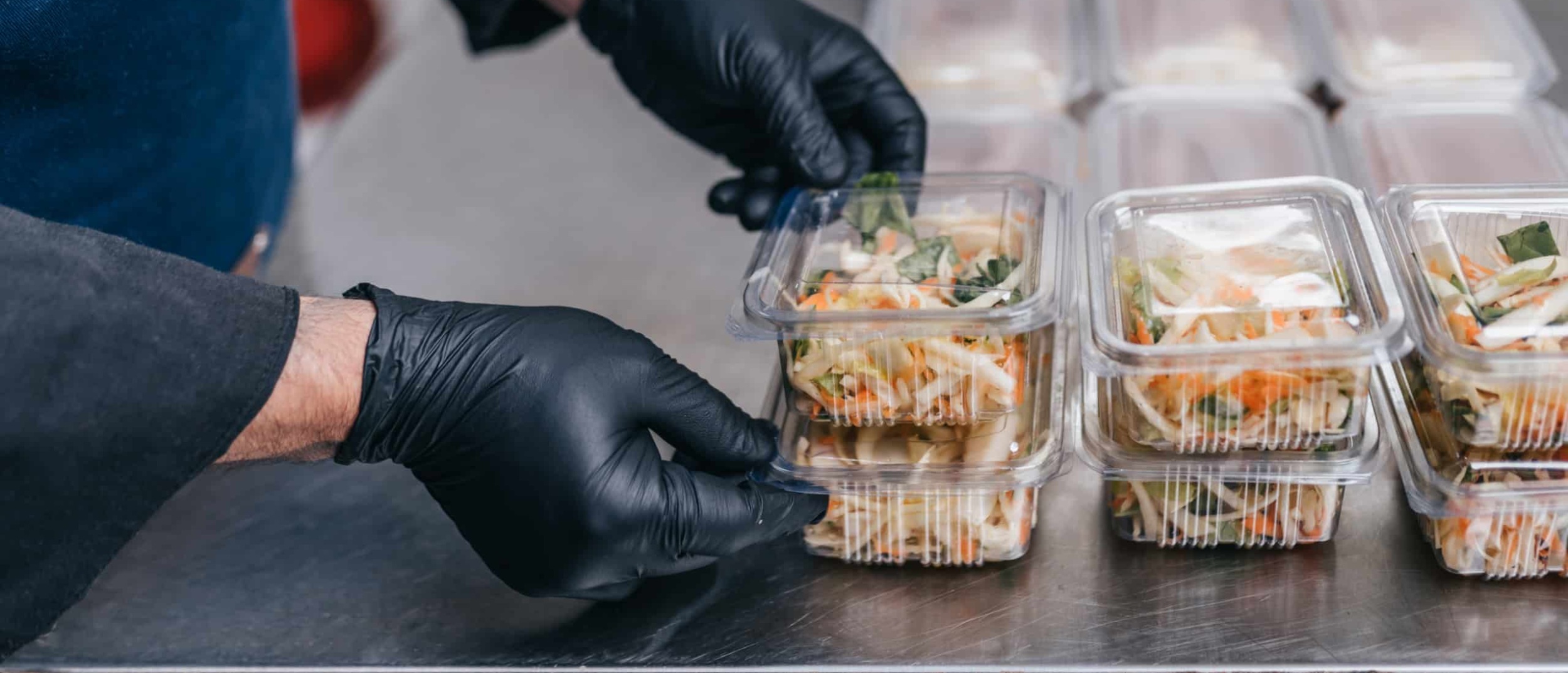 Food being packed in clear, disposable food packages