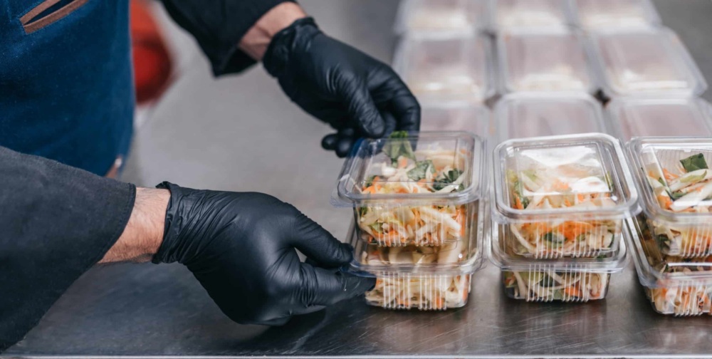 Food being packed in clear, disposable food packages.